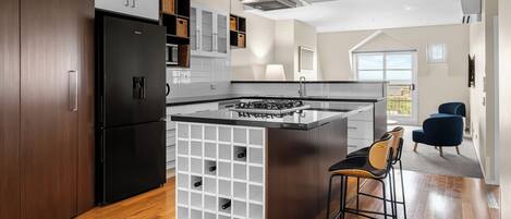 A modern kitchen with a central island, built-in wine storage, and a view to the outdoors.