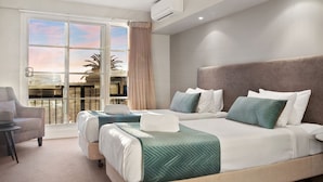 A hotel room with a large bed, a sofa, a small table, and a balcony with a view. - Deep Blue Hotel & Hot Springs (Warrnambool)