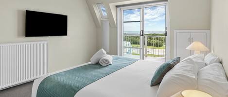 A hotel room with a bed, a TV, a window with a view, and a radiator.