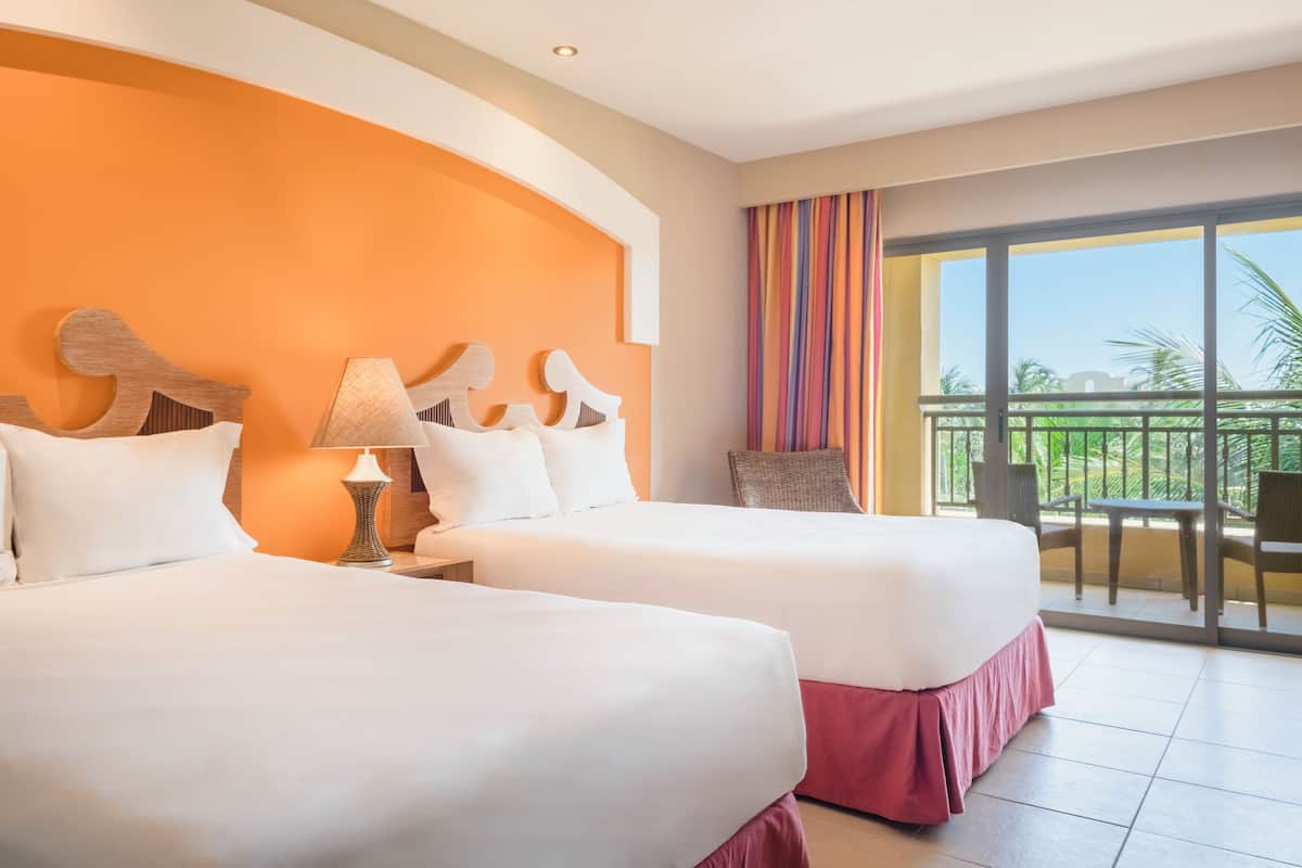 Une chambre d’hôtel avec deux lits, un balcon offrant une vue et une grande fenêtre avec des rideaux.