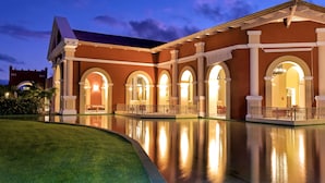 A large, well-lit building with multiple arched doorways and a reflective pool in front. - Iberostar Waves Bahia - All Inclusive (Mata de São João)