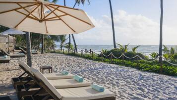 Rannalla, aurinkotuoleja, rantalentopallomahdollisuus