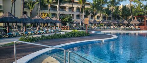 A resort pool area with lounge chairs and palm trees.