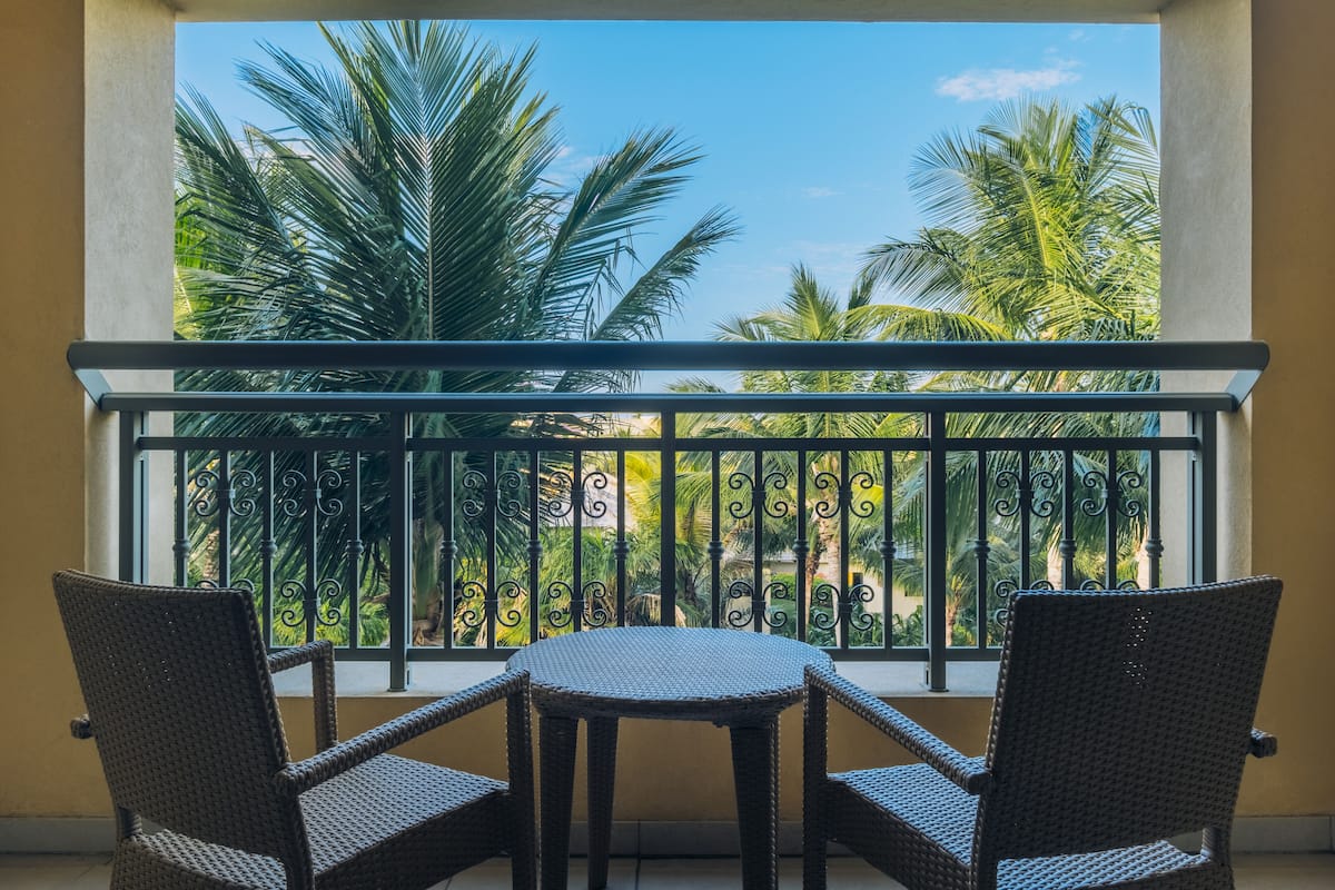 Un balcon offrant une vue sur des palmiers et un ciel dégagé.