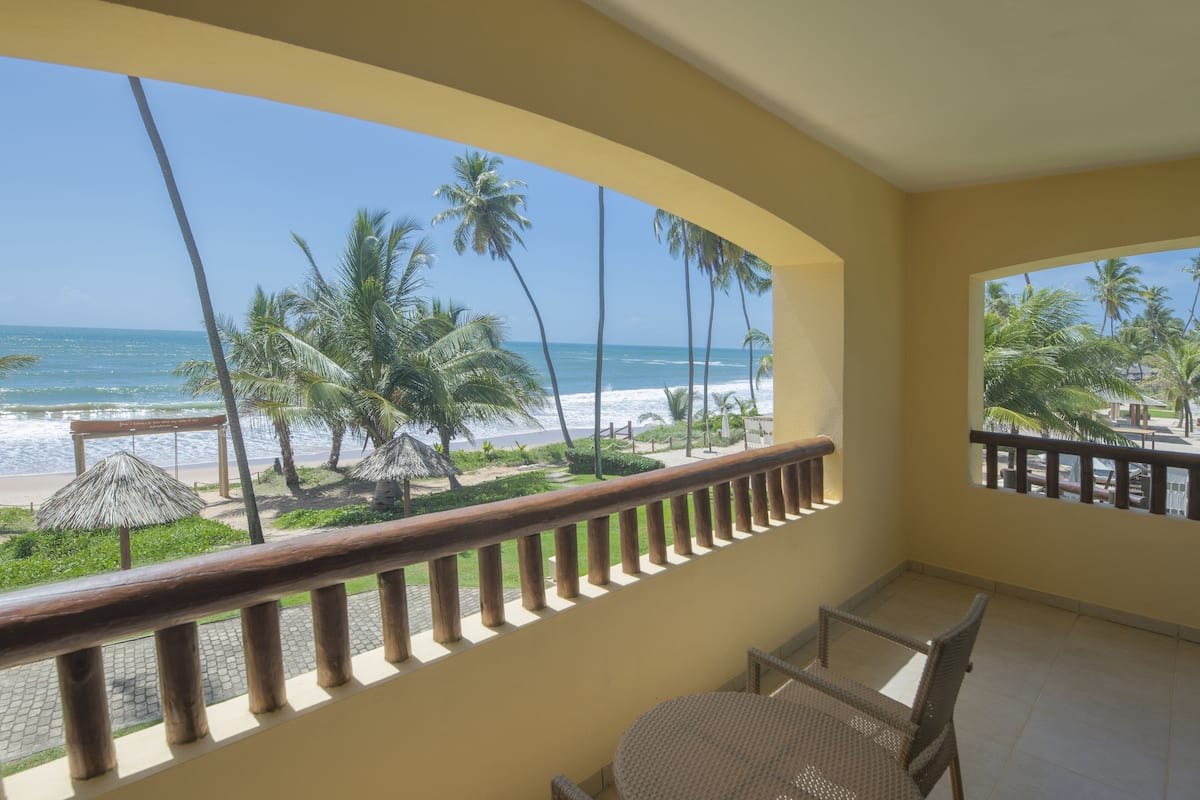 Un balcon avec vue sur la plage, les palmiers et l’océan.