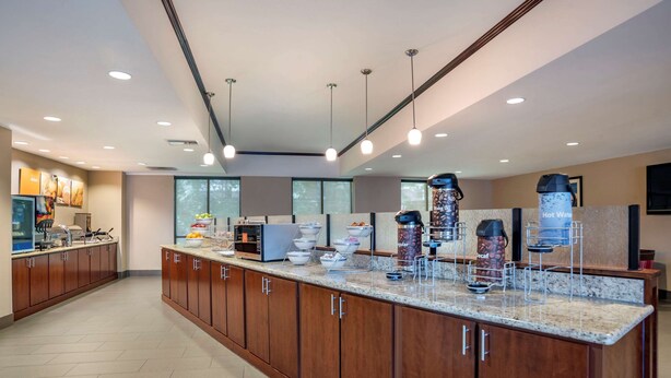 A modern kitchen with wooden cabinets, granite countertops, and various appliances. - Comfort Suites Mobile (Mobile)