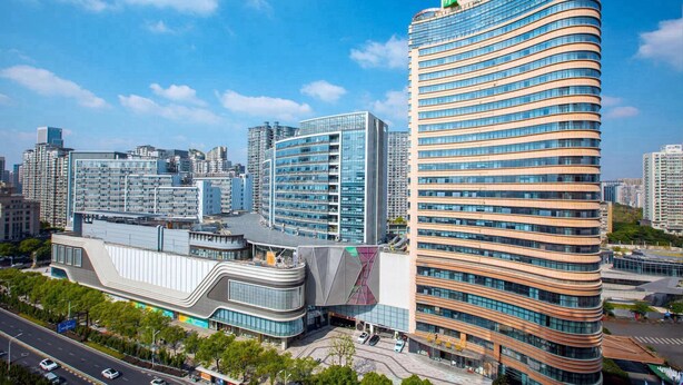 A modern hotel with a curved facade, multiple floors, and a prominent sign at the top.