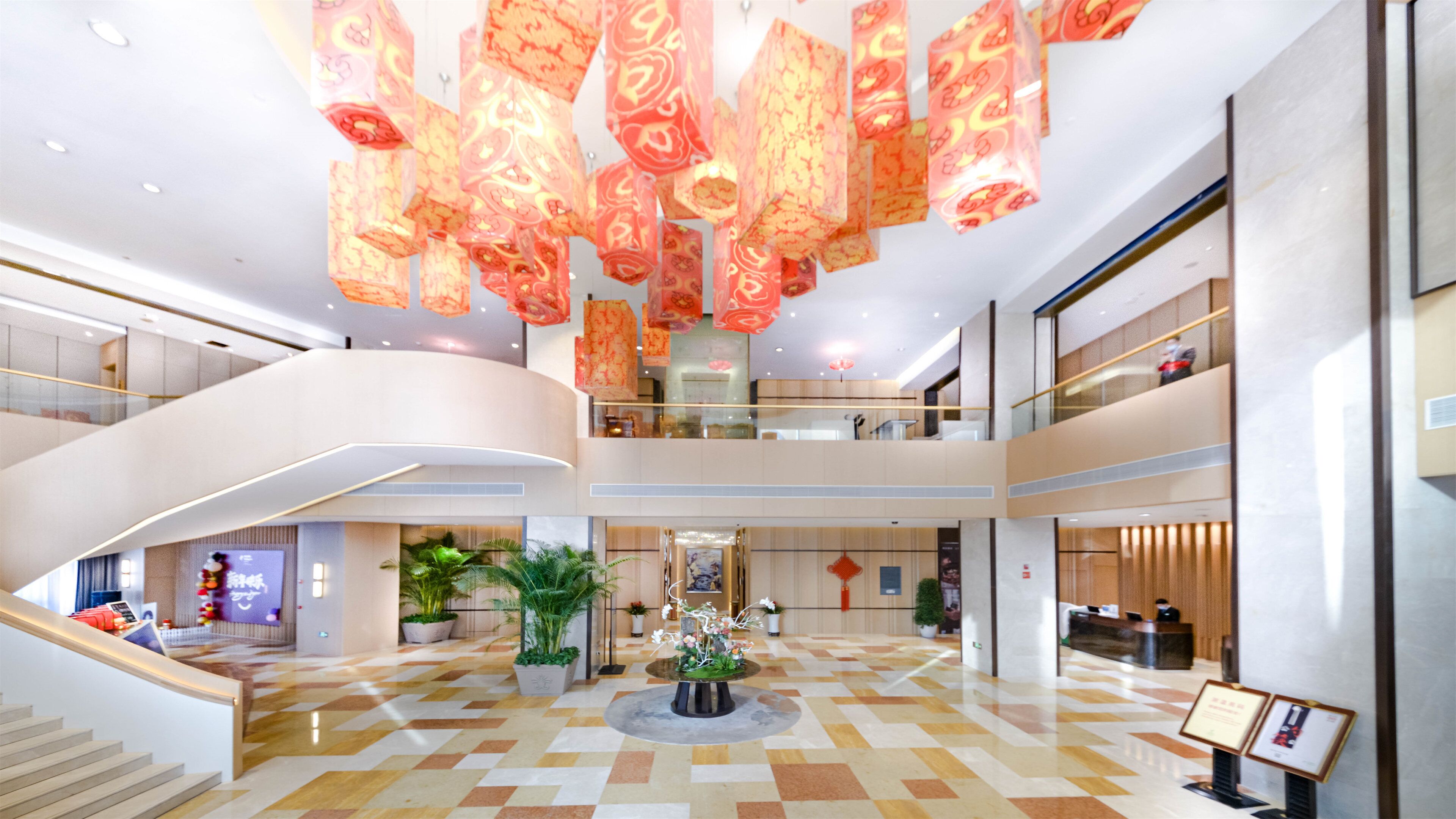 Un hall d’entrée spacieux, doté d’un sol à carreaux, d’une composition florale centrale et d’un escalier menant à un niveau supérieur.