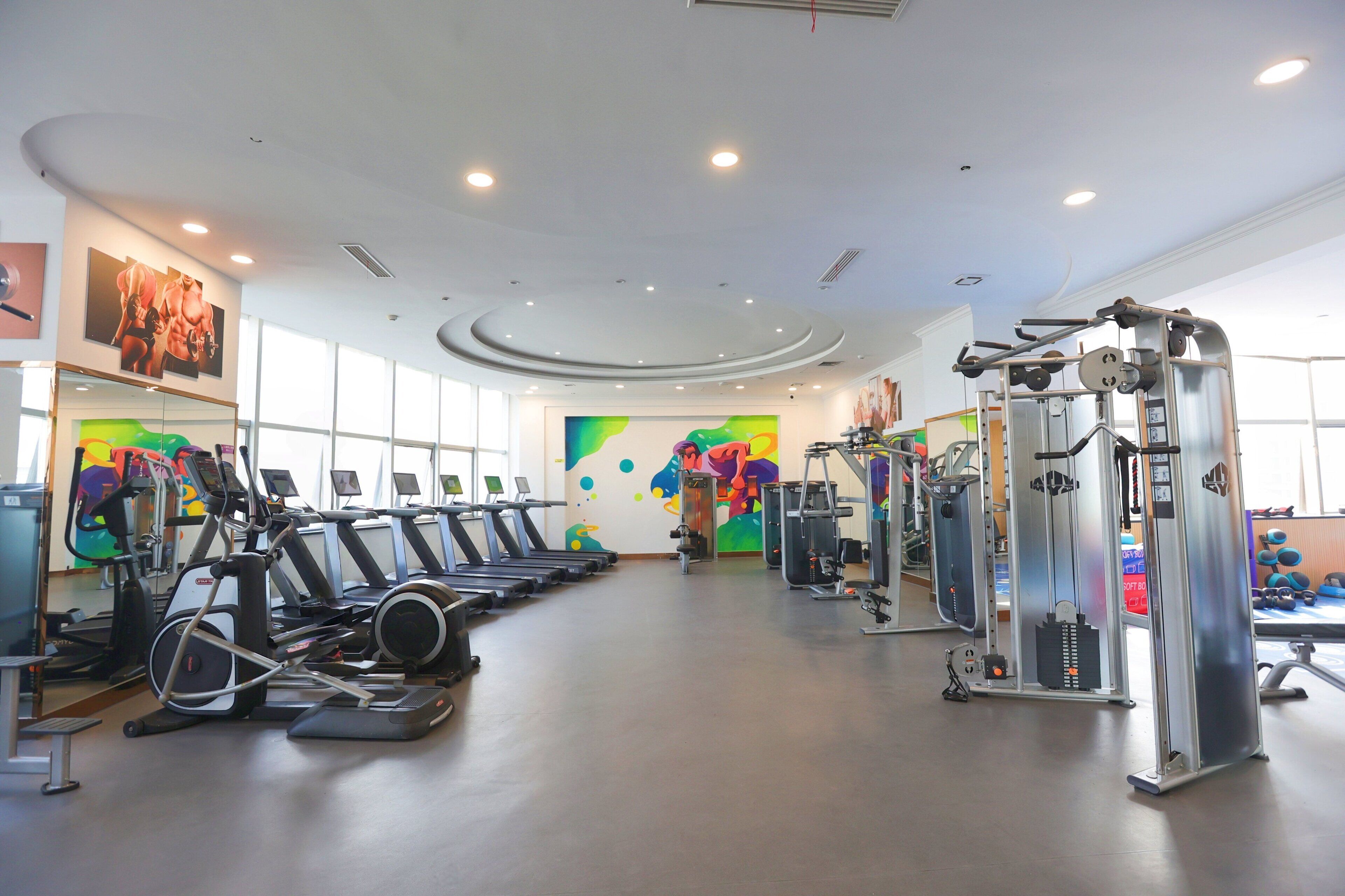 Un gimnasio con cintas de correr, máquinas de pesas y pelotas de ejercicio.