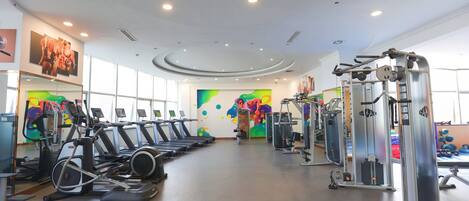 Un gimnasio con cintas de correr, máquinas de pesas y pelotas de ejercicio.