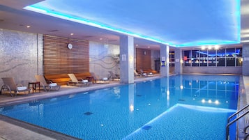 A swimming pool with lounge chairs and a clock on the wall.