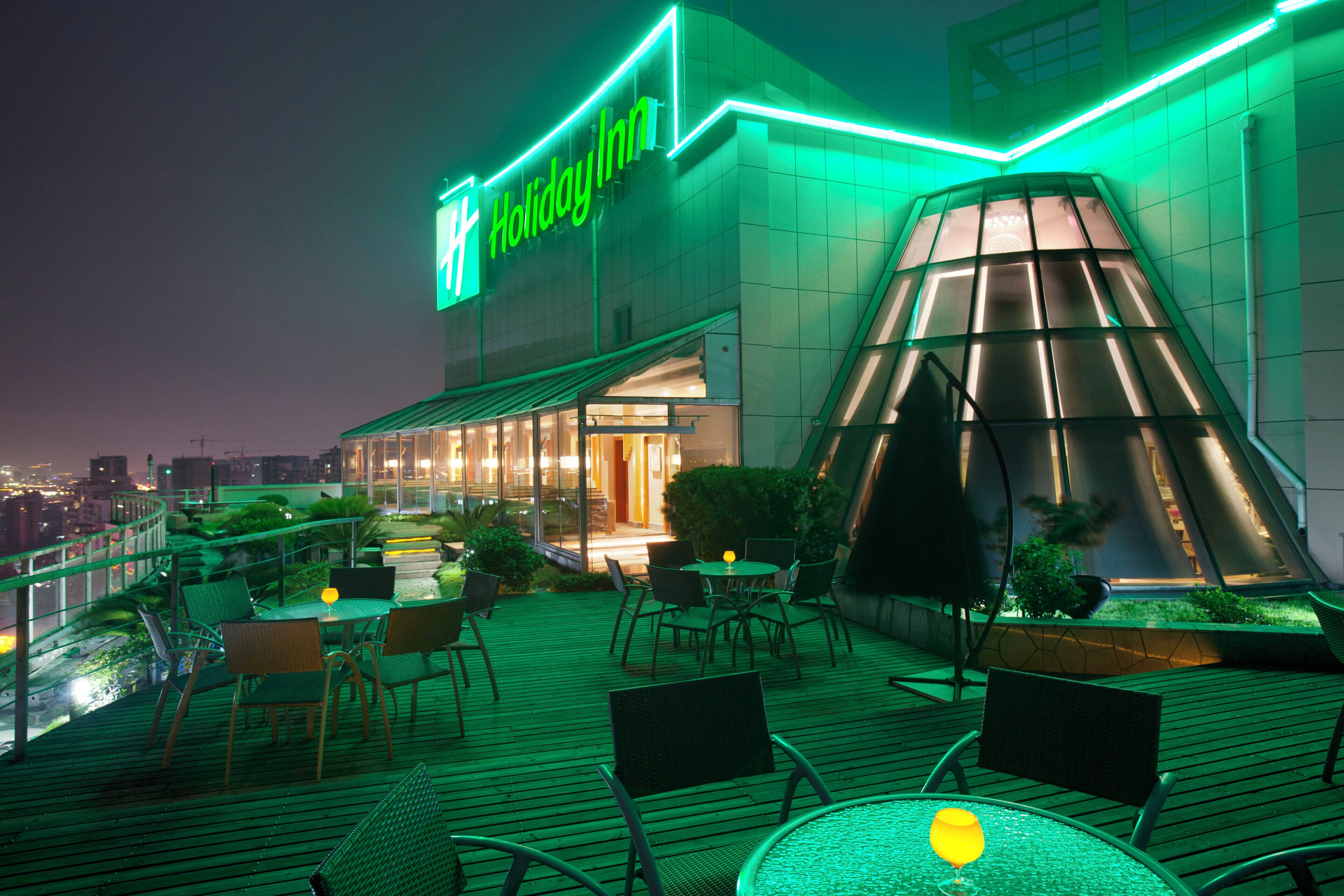Holiday Inn -hotelli, jossa on kattoterassi, ulkoilmaistumapaikkoja ja lasista tehty pyramidimainen rakennelma.
