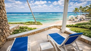 Un patio frente a la playa con dos sillones, un muro de piedra y vista al océano.