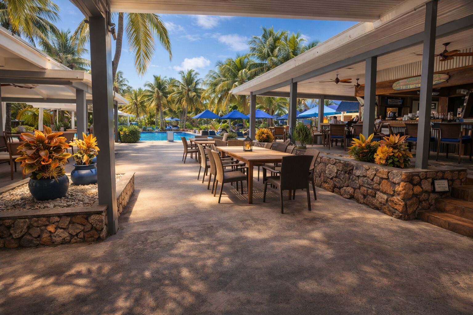 Une terrasse extérieure avec des tables et des chaises, une piscine et des palmiers.