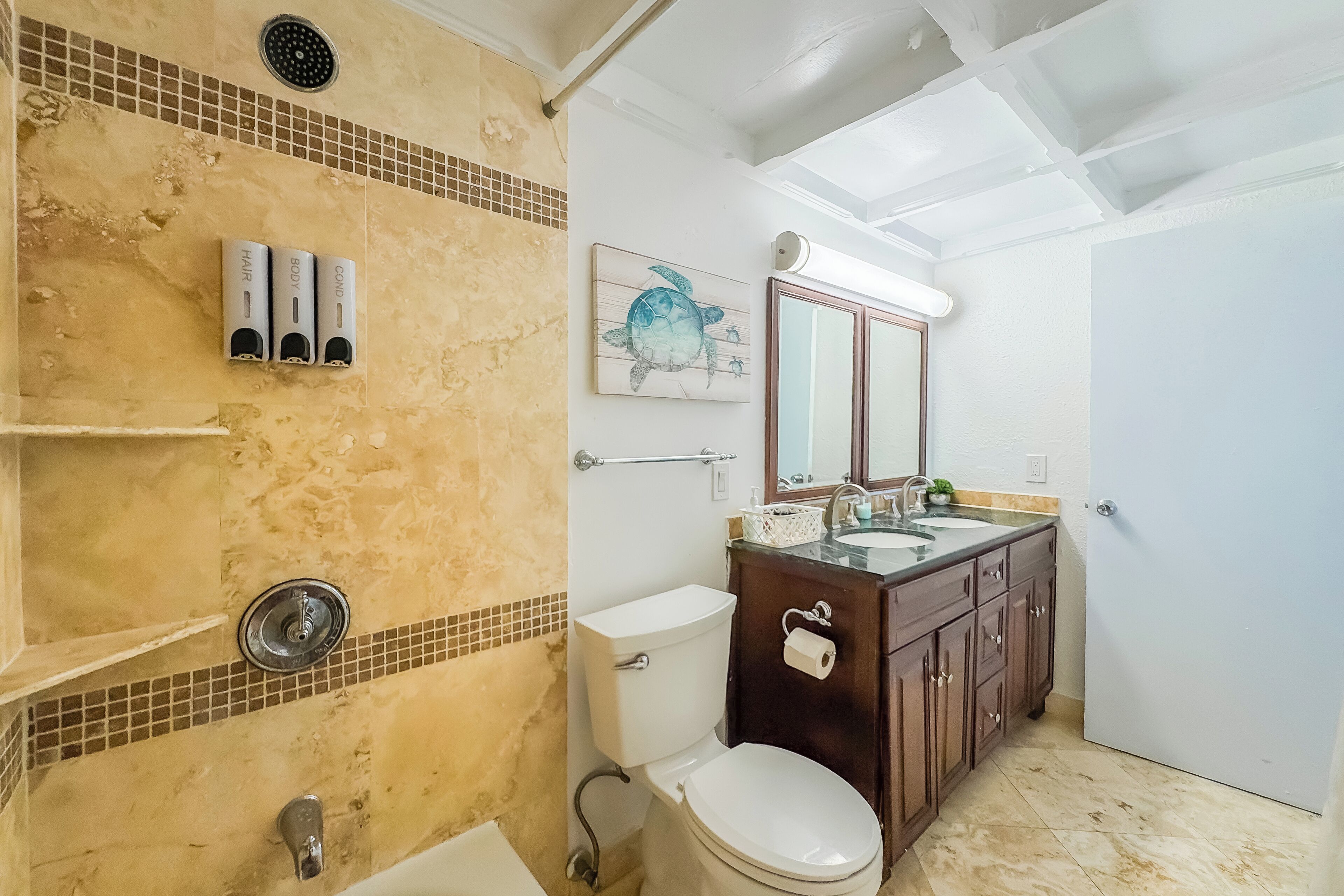 Een badkamer met een douche, toilet en een wastafel met spiegel.