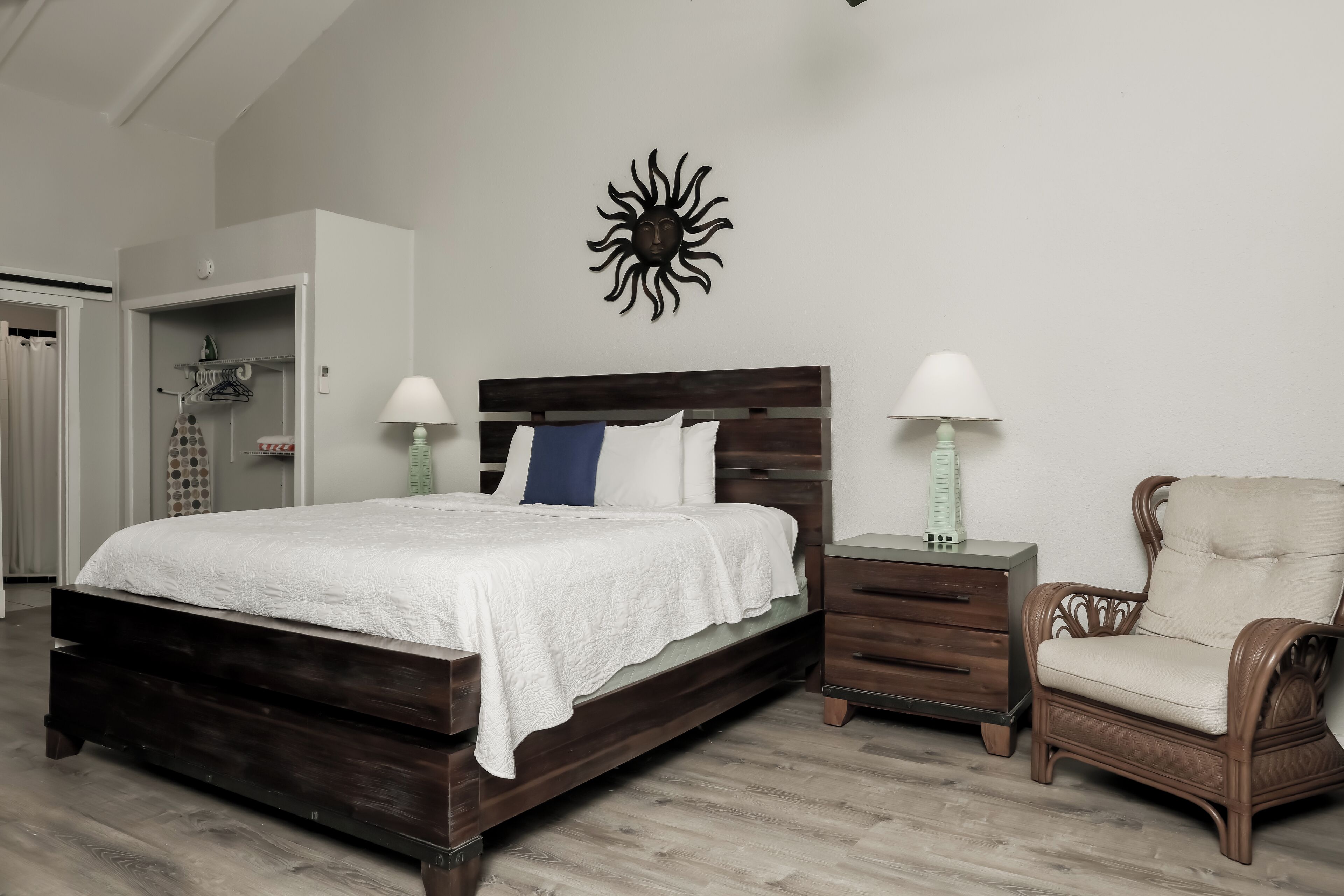 Una camera da letto con un letto di legno, due comodini con lampade, una sedia e un armadio.