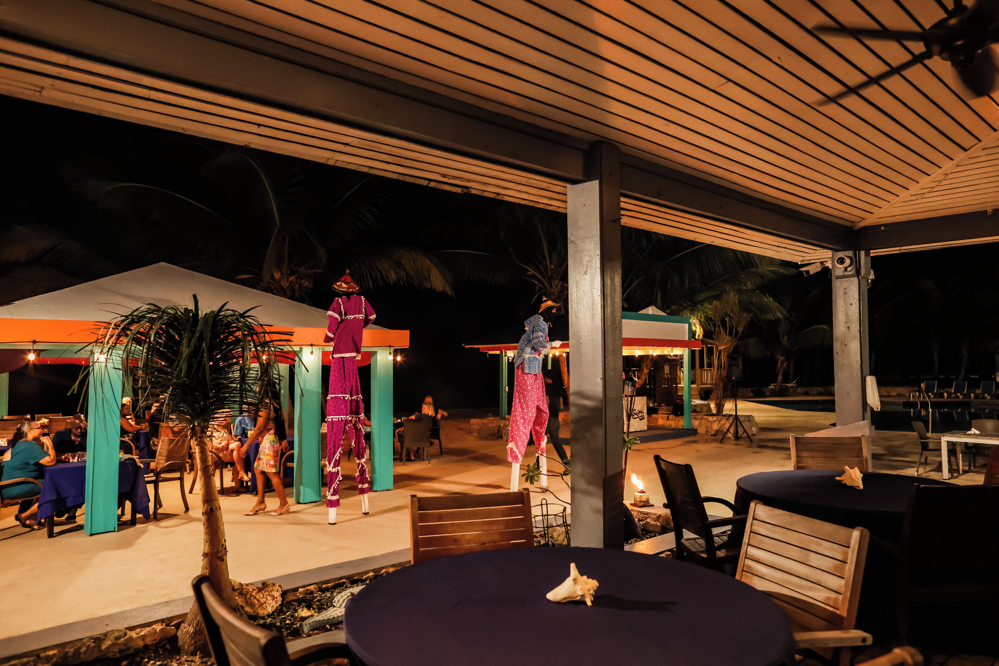 An outdoor dining area with tables and chairs, a covered seating area, and a decorative structure.