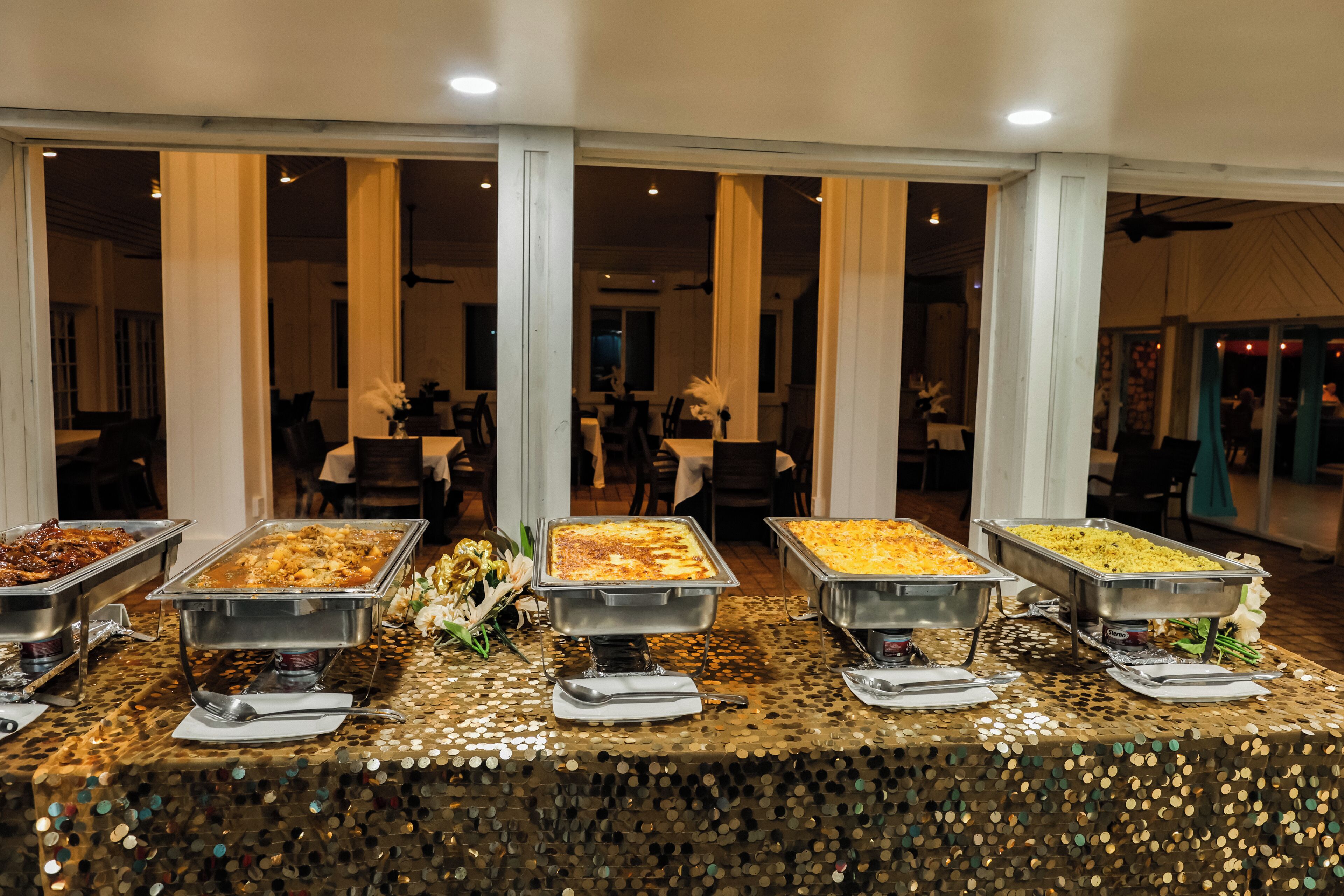 A buffet setup with multiple serving dishes, a decorative table, and a view of the dining area in the background.