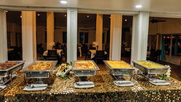 A buffet setup with multiple serving dishes, a decorative table, and a view of the dining area in the background.
