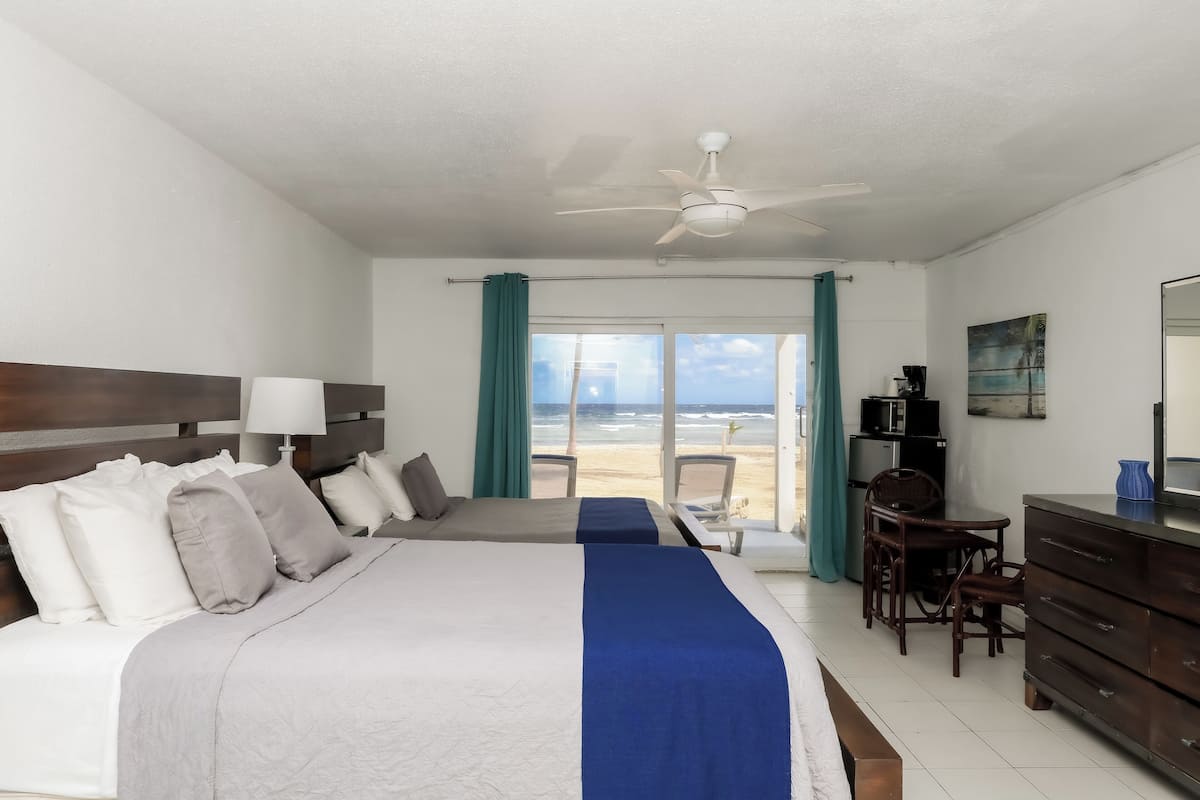 Une chambre d’hôtel avec un lit, un bureau, une chaise, une commode et une vue sur la plage.