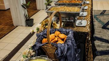 A buffet setup with various food items and a large bowl of lentils.