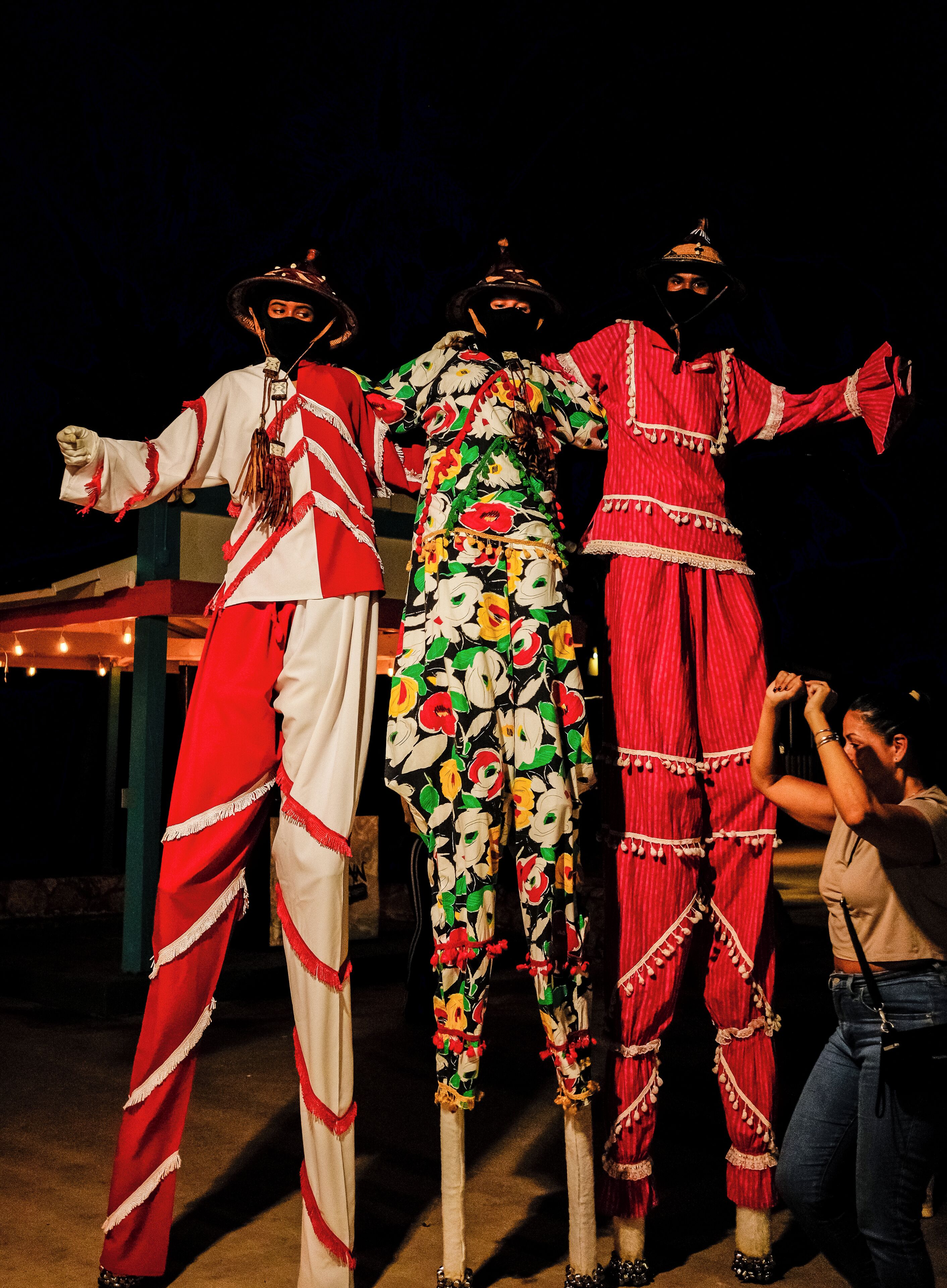 Three individuals in traditional attire standing outdoors at night.