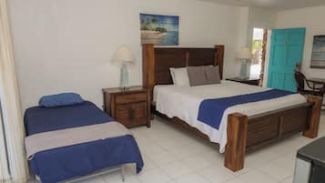 A hotel room with two beds, a wooden headboard, a painting on the wall, and a teal door.