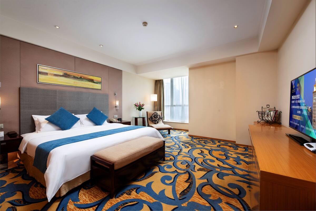 Een hotelkamer met een groot bed, een bureau, een televisie en een raam.