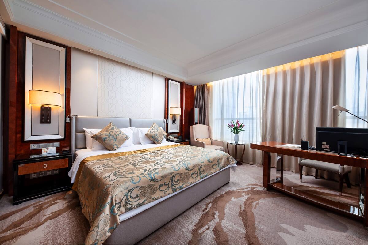 Een hotelkamer met een groot bed, een bureau, een stoel, een televisie en een nachtkastje.