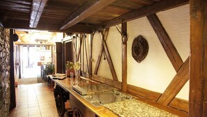 A rustic kitchen with wooden beams, a stone wall, and a wooden counter with a sink. - Hotel Petzengarten (Nuremberg)