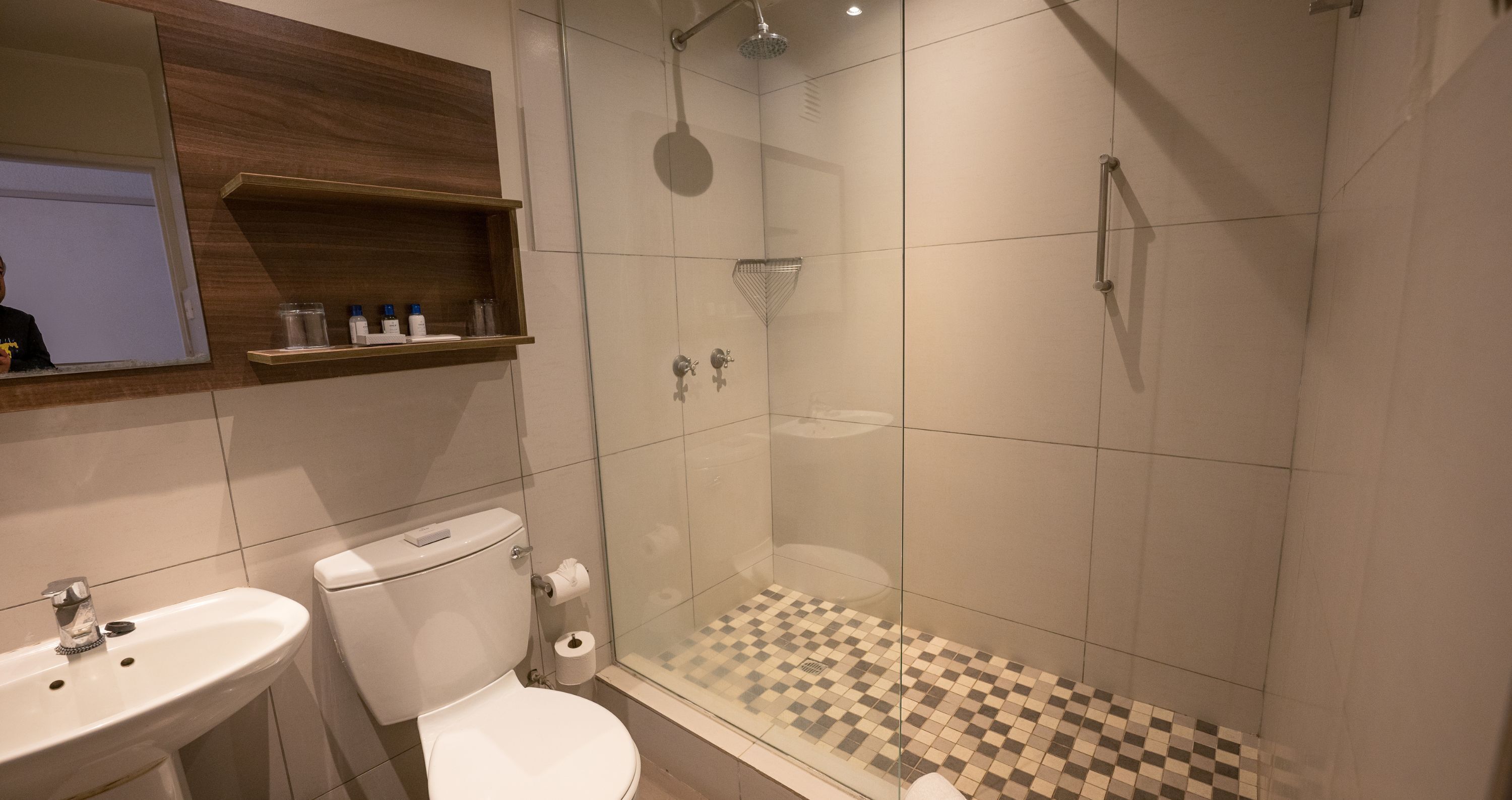 Un baño moderno con ducha de vidrio, inodoro y lavamanos.