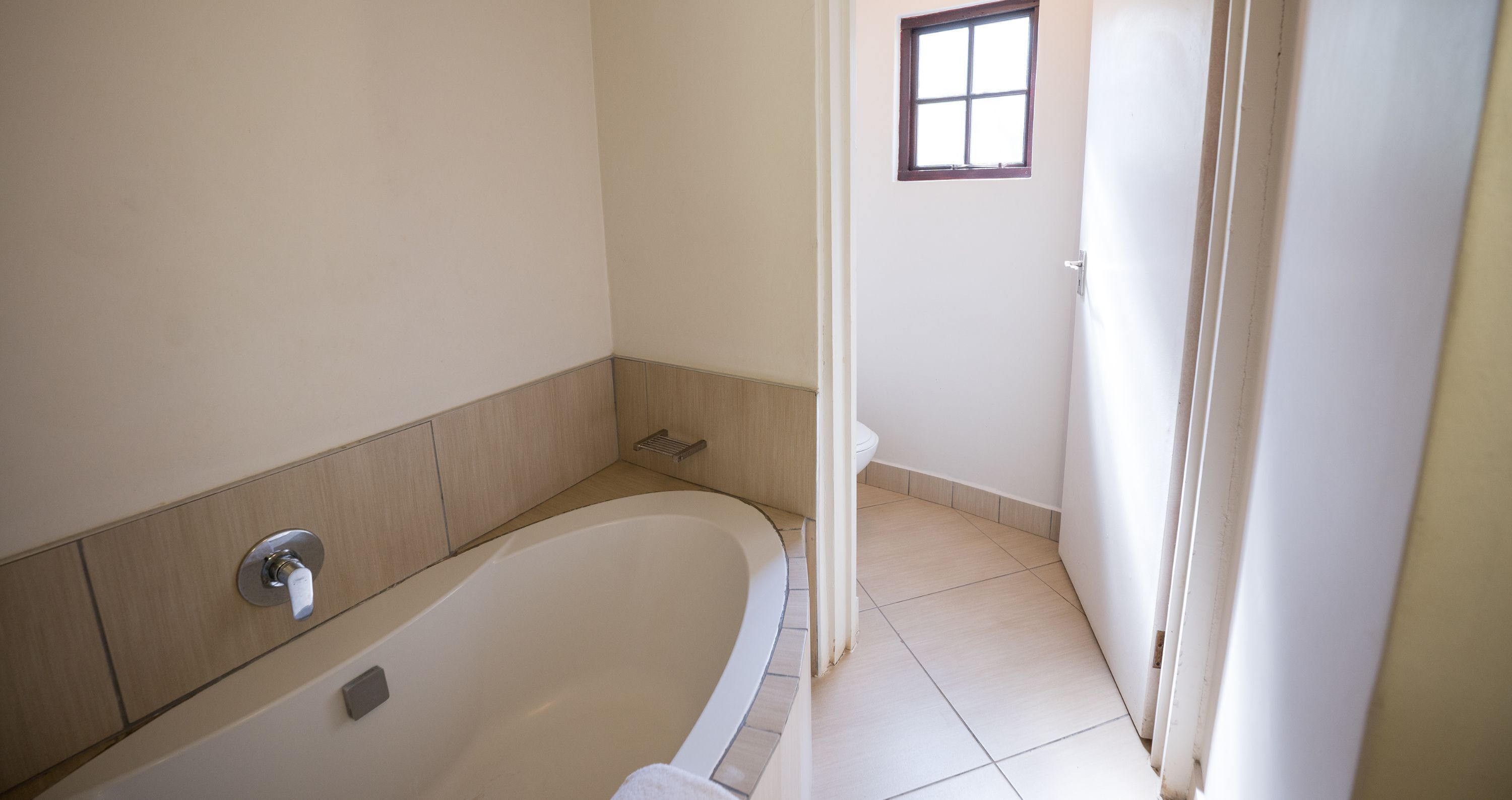 A bathroom with a bathtub, a window, and a toilet.