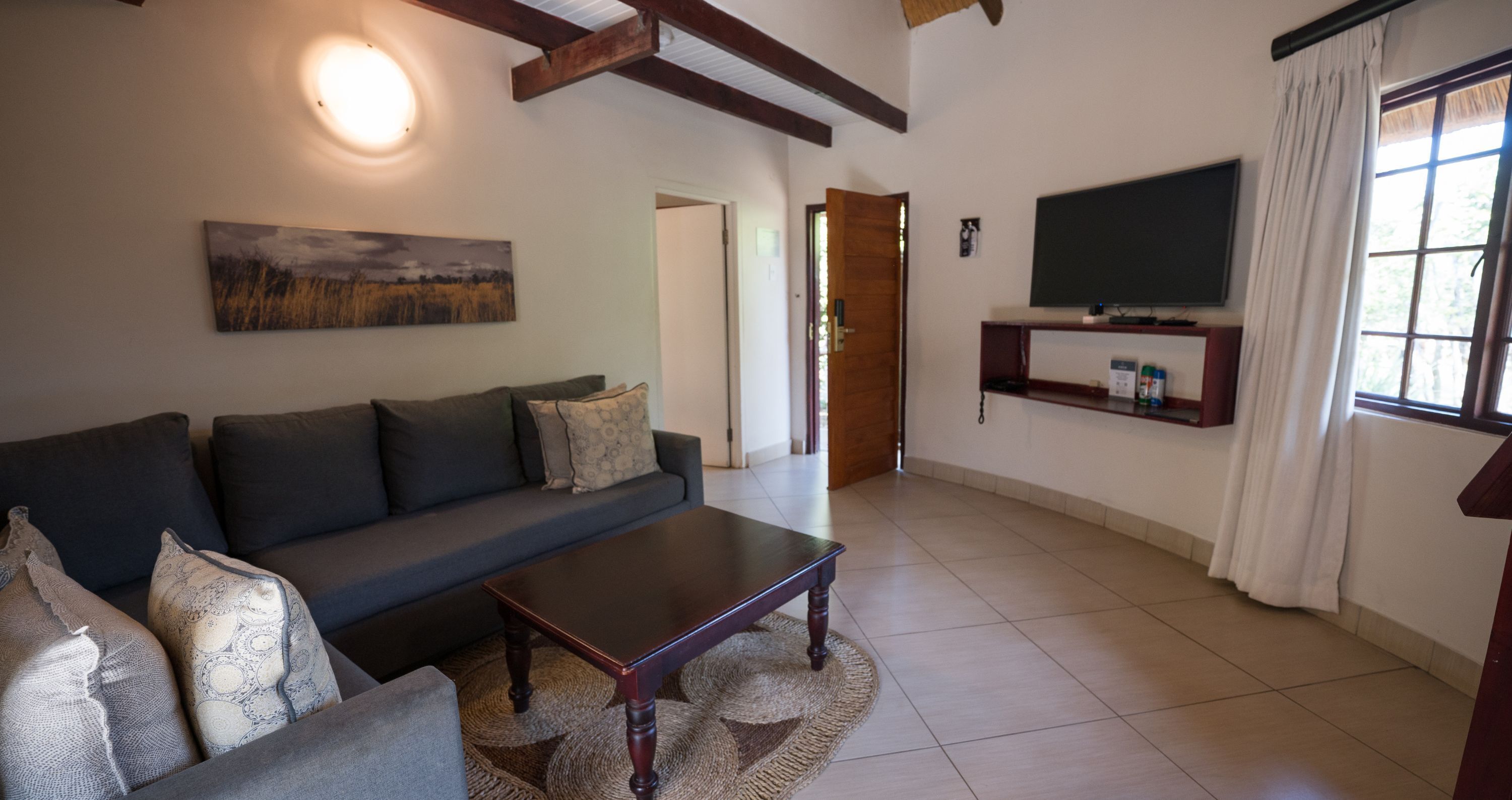 A living room with a sofa, coffee table, and a flat-screen TV mounted on the wall.