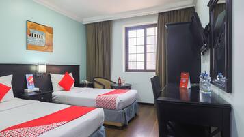 A hotel room with two beds, a desk, a chair, a TV, a window, and a painting on the wall.