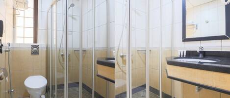 A bathroom with a glass-enclosed shower, a toilet, and a sink with a mirror above it.