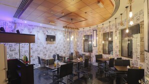 Un restaurante con pared de diseño, techo de madera y lámparas colgantes. Mesas y sillas dispuestas para comer.
