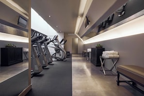 A gym with exercise equipment, a bench, and a mirror.