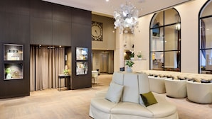 A spacious lobby with a large sofa, a chandelier, and a clock on the wall.