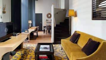 A modern living room with a sofa, coffee table, and a TV. There is a staircase leading to another level.