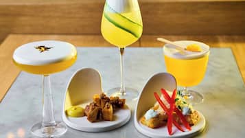 Trois boissons et deux assiettes de nourriture sur une table en marbre.