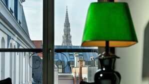 A view from a window with a green lamp, overlooking a historic building with a tall spire. - The Dominican, Brussels, a Member of Design Hotels (Brussels)