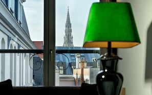 Vista desde una ventana con una lámpara verde, que da a un edificio histórico con una aguja alta.
