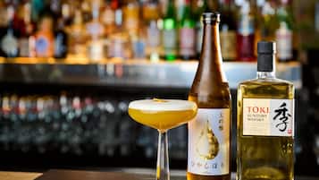 A bar setting with a martini glass, a bottle of Toki Suntory whisky, and a bottle of sake.
