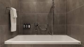 A modern bathroom with a bathtub, a handheld showerhead, and a towel rack.