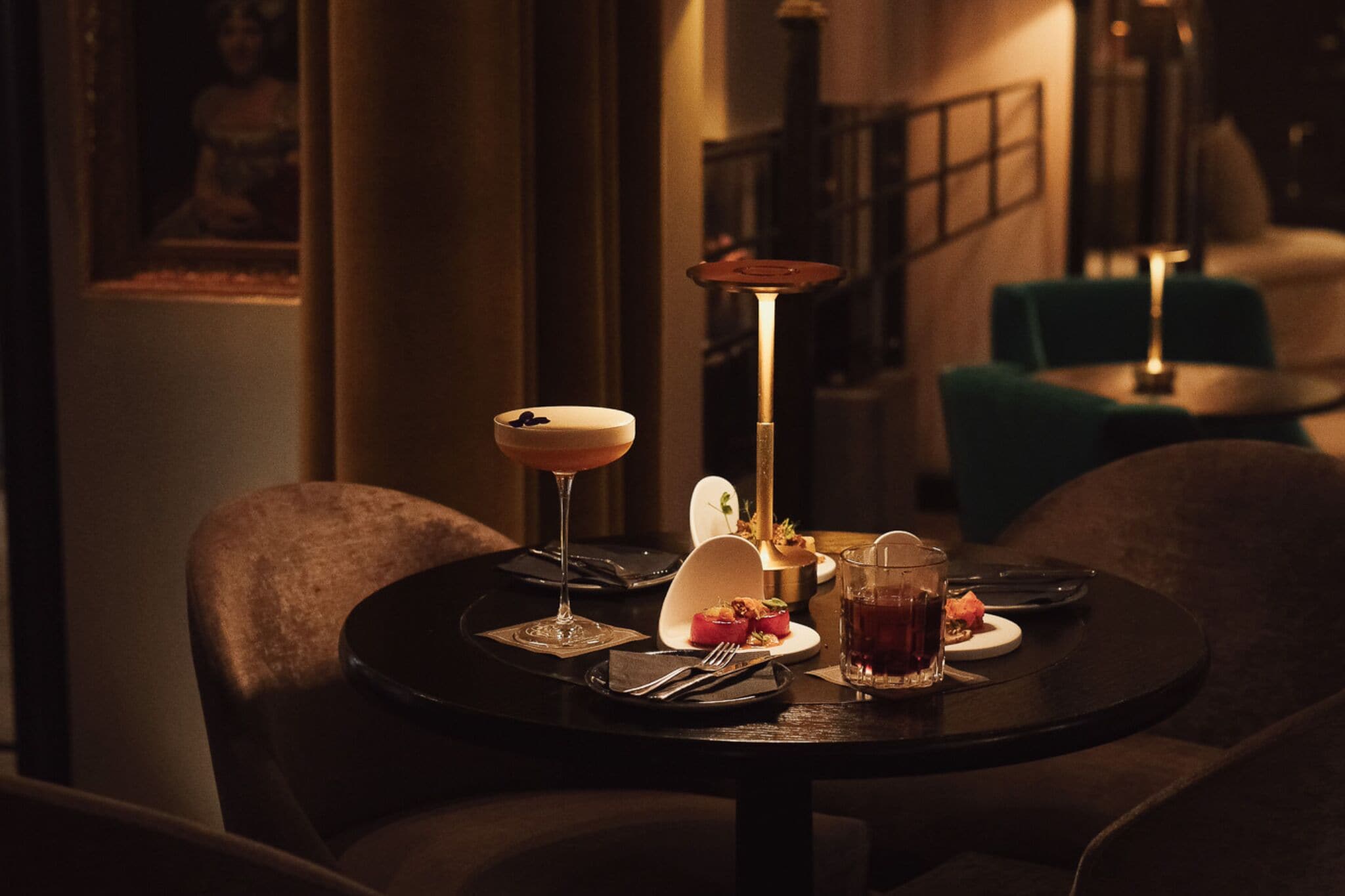 A dimly lit dining area with a table set for two, featuring a candle, a glass of red wine, and a dessert plate.