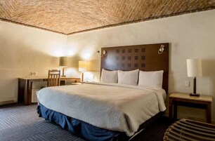 A hotel room with a large bed, a desk, and a chair.