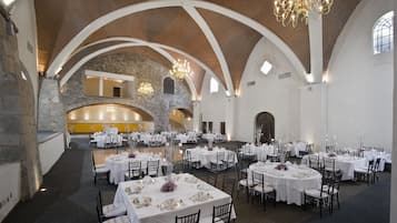 Un salón de banquetes con mesas redondas, manteles blancos y candelabros.