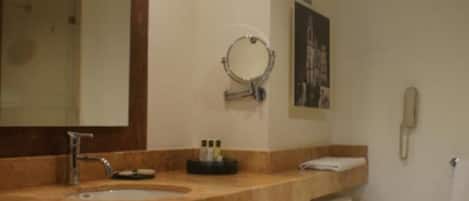 A bathroom with a marble sink, a large mirror, a toilet, and a telephone.