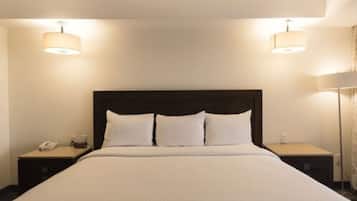 Una habitación de hotel con una cama grande, dos mesitas de noche, un teléfono y dos lámparas de pared.