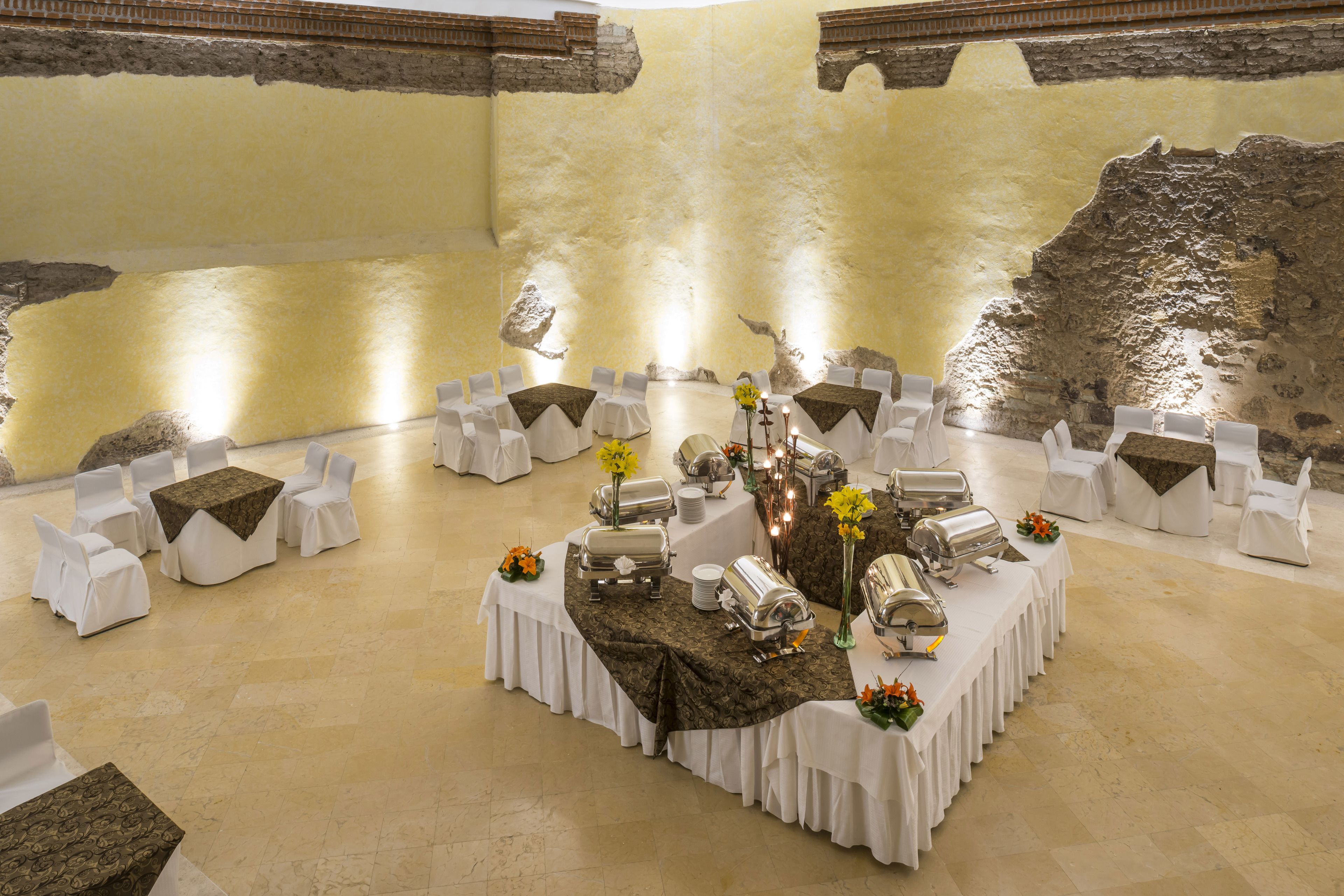 A banquet hall with round tables covered in white tablecloths, silverware, and floral centerpieces.